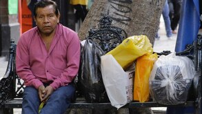 Ciudadano sentado junto a sus compras almacenadas en bolsas plásticas