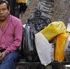 Ciudadano sentado junto a sus compras almacenadas en bolsas plásticas