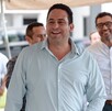 Se observa a un hombre sonriendo que viste una camisa azul celeste.