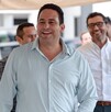 Se observa a un hombre sonriendo que viste una camisa azul celeste.