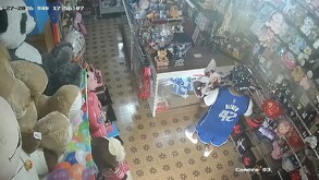 Se observa a un hombre que viste short y playera azul, trae unas flores en la mano.