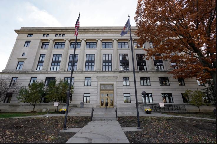 Vista del exterior del tribunal del condado Genesee en Flint, Michigan con árboles y bandera alrededor