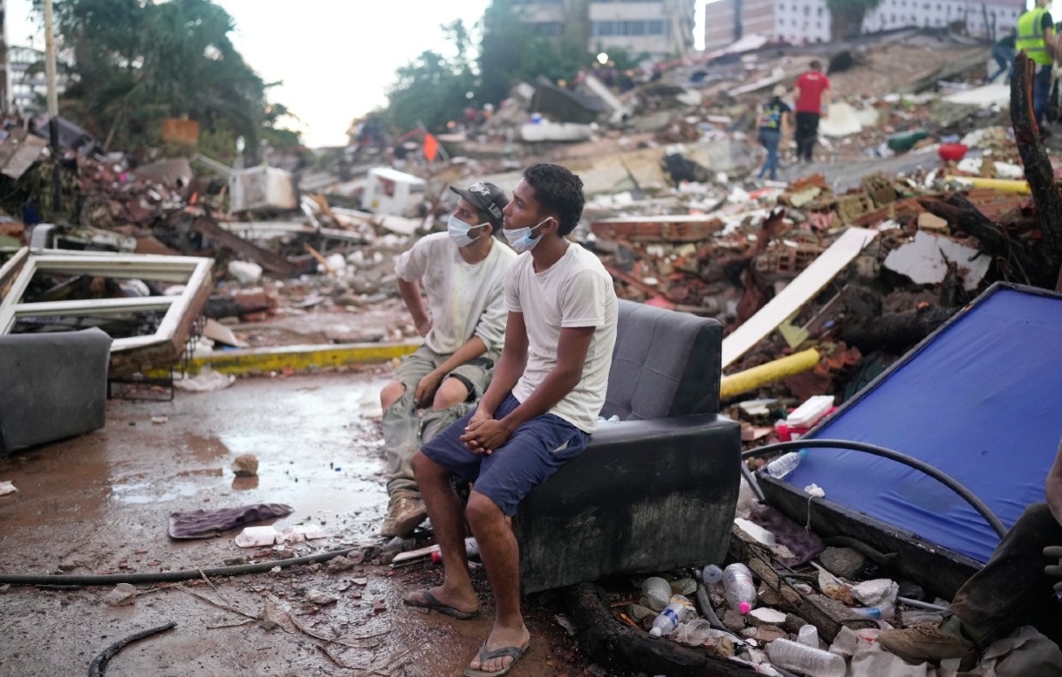 Residentes que ayudan en las labores de rescate se sientan entre escombros que dejaron los terremotos en La Guaira, Venezuela, el 30 de junio de 2026.