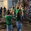 Hombres y mujeres con playeras de la Selección Mexicana vistos de espaldas con las manos en alto caminando hacia policías de la Guardia Nacional en Guadalajara