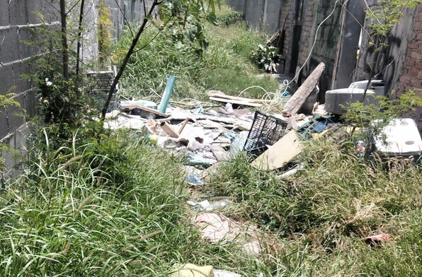 Se observa basura tirada entre matorrales.