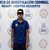 Se observa un hombre que viste pantalón de mezclilla y playera; tiene tapados los ojos.