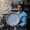una mujer sostiene un plato de talavera dentro de un taller en puebla