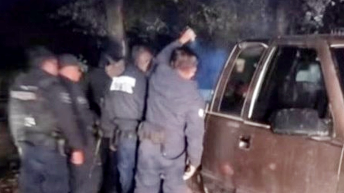 Policías apuntando con una lámpara a la batea de una camioneta.
