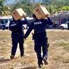 Personas con uniforme policial cargando cartones de cerveza.