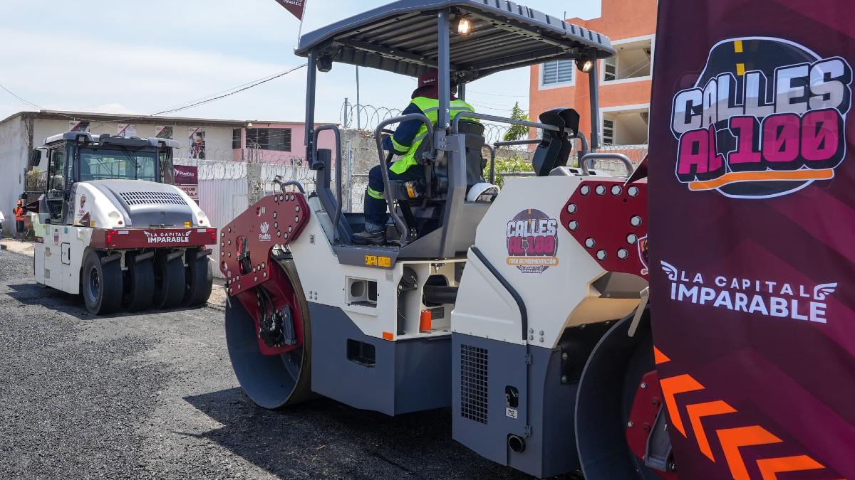Tren de pavimentación pasa por calles de la capital con logo de programa Calles Al 100