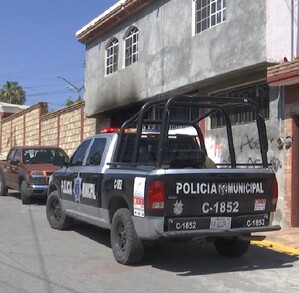 Se observa una patrulla afuera de una casa que tiene graffitis.