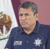 Hombre con traje policiaco hablando ante un micrófono.