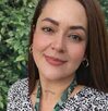 Periodista Roxana Guzmán sonriendo para una fotografía en un campo.