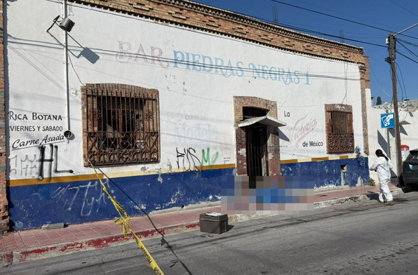 Se observa un cuerpo tendido en la banqueta afuera de un establecimiento con letras que dicen Bar Piedras Negras 1.