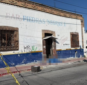 Se observa un cuerpo tendido en la banqueta afuera de un establecimiento con letras que dicen Bar Piedras Negras 1.