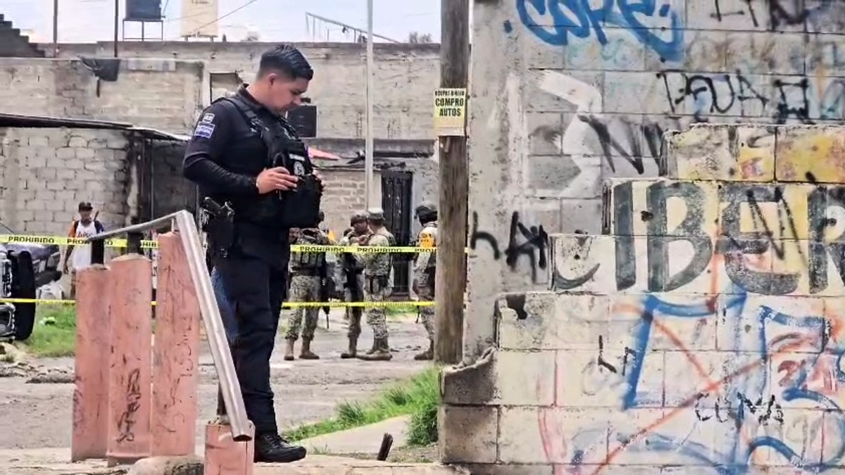 Policía de Jalisco viendo hacia abajo en sitio donde se halló un cuerpo con militares detrás en un área acordonada