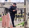 Policía de Jalisco viendo hacia abajo en sitio donde se halló un cuerpo con militares detrás en un área acordonada
