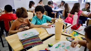 Niños realizando actividades de dibujo en mesas dentro de un salón de clases