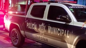 Vista lateral de una patrulla de la Policía de Zapopan detenida en un cruce peatonal con automóviles detrás