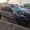 Camioneta RAM de lujo destruida de la parta frontal y trasera siendo remolcada por una grúa con un policía vial delante y una plaza comercial en el fondo