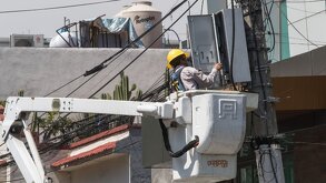 un trabajador de cfe manupula cables en un poste