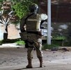 Militar del Ejército Mexicano visto de espaldas en la esquina de una calle con un poste, un árbol y una camioneta alrededor