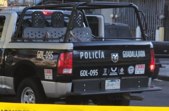 Patrulla de la Policía de Guadalajara con policías apoyados en el cofre dentro de un área acordonada por una cinta policiaca amarilla