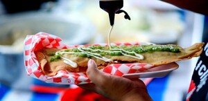 Hombre sujeta un molote en un plato mientras le echa crema.