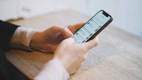 Un teléfono celular con una app de mensajería mientras lo sostiene un par de manos