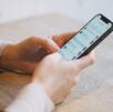 Un teléfono celular con una app de mensajería mientras lo sostiene un par de manos