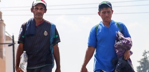 Hombres migrantes caminan por calles en su paso