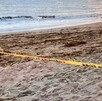 Costa de una playa de Nayarit con vista del mar, la arena y una cinta policiaca color amarillo acordonando el área tras el hallazgo de un cuerpo