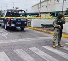 Militar del Ejército Mexicano parado con un arma larga delante de un área acordonada con una patrulla de la Policía de Zapopan en el sitio