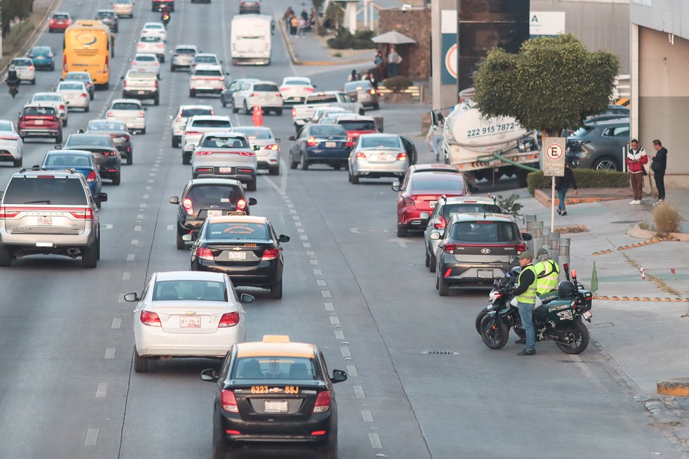 Vehículos cruzando en una avenida de Puebla con poco espacio para peatones.