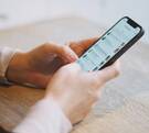 Un teléfono celular con una app de mensajería mientras lo sostiene un par de manos