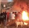Pobladores reunidos frente a un vehículo incendiado en llamas.