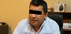 Se observa a un hombre con camisa azul celeste y los ojos tapados con cintilla negra.