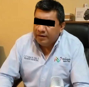 Se observa a un hombre con camisa azul celeste y los ojos tapados con cintilla negra.