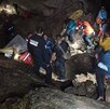 personas con cascos, lámparas y cuerdas dentro de una gruta realizan labores de rescate