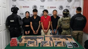 Tres hombres y una mujer esposados y con los ojos censurados con blur siendo detenidos en medio de policías de Colima con armas y municiones delante