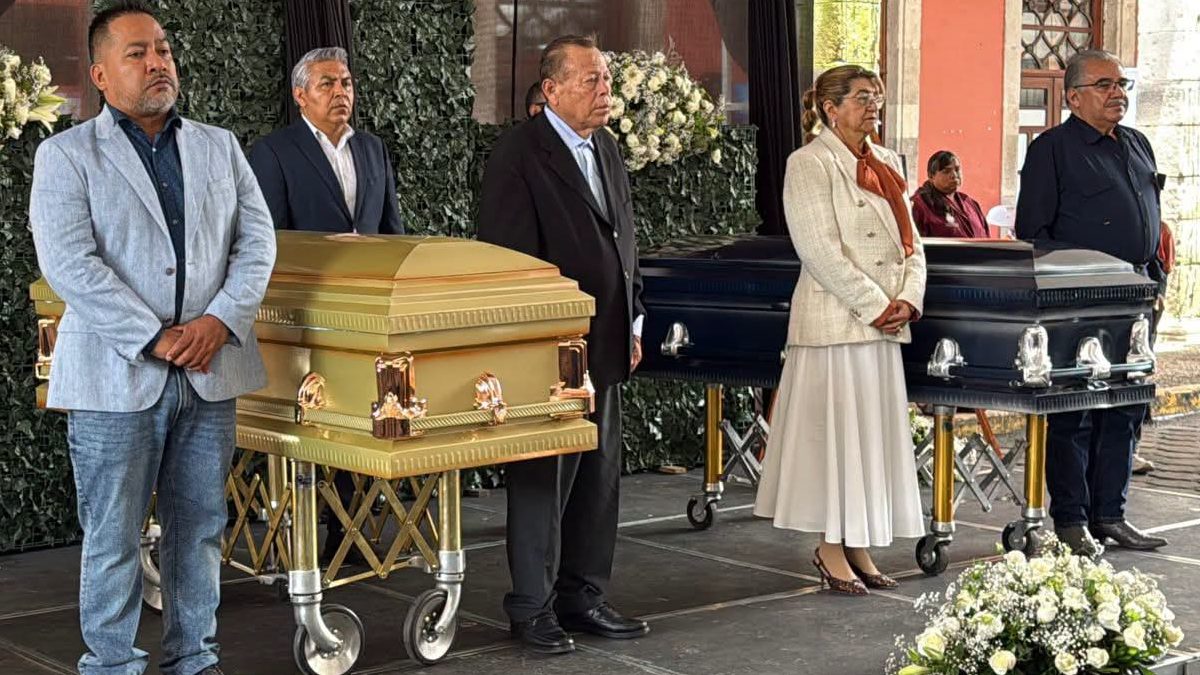 Personas paradas junto a dos féretros en el municipio de Huauchinango.