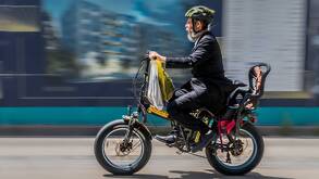 Un hombre vestido con traje manejando una motobici eléctrica