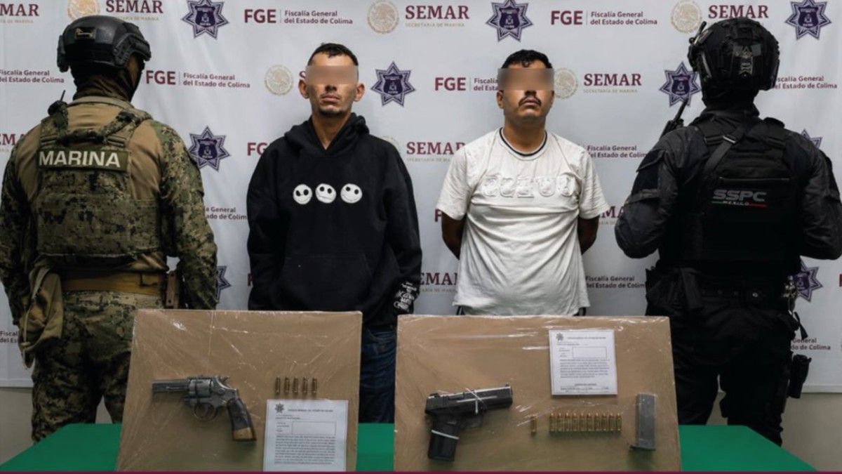 Dos hombres esposados y con los ojos censurados con un recuadro con blur siendo detenidos en medio de policías de Colima con armas y municiones delante