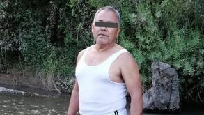 Hombre de la tercera edad y una playera de manga corta posando junto a un río.