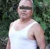 Hombre de la tercera edad y una playera de manga corta posando junto a un río.