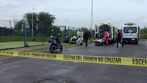 Vecinos y paramédicos de la Cruz Verde y la Cruz Roja con ambulancias dentro de un área acordonada por la policía al lado de un vaso regulador