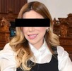 Se observa a una mujer sonriendo con ojos cubiertos y viste una camisa blanca y chaleco negro.