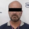 Se observa a un hombre con ojos tapados, con playera y pantalón de mezclilla.