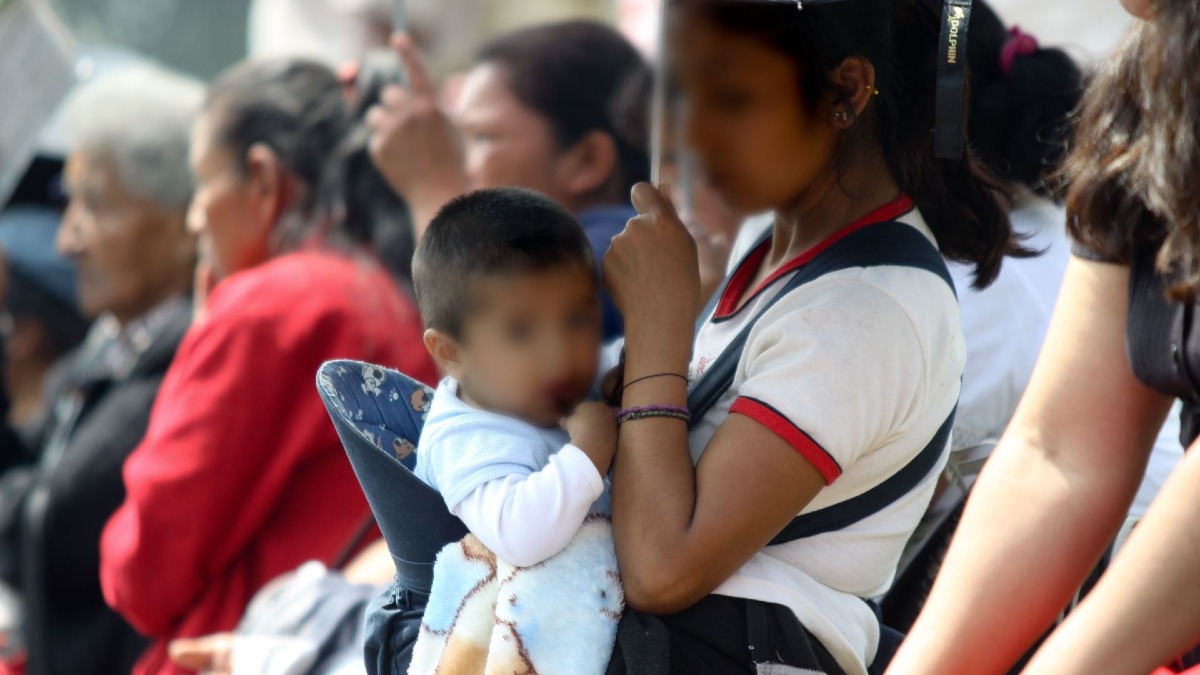 una mujer cargando a un bebé en un lugar público
