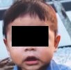 Bebé con playera azul y los ojos censurados con fondo negro